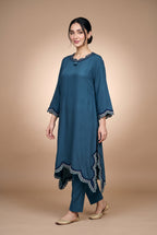 Model wearing the Petrol Scallop Suit in petrol blue, full-length view showing the scalloped handkerchief hem