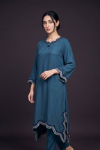 Model wearing the Petrol Scallop Suit, showing the scalloped neckline and lace-edged sleeves